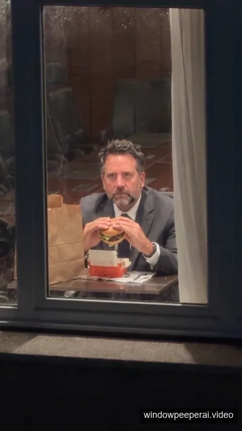 AI-generated middle frame showing the subject eating a burger and staring through the window