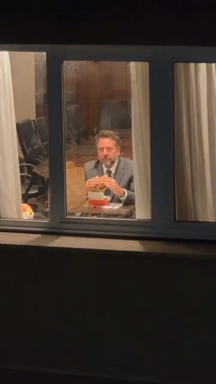 AI-generated Window Peeper result showing a suited adult through one lit apartment window